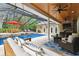 Relaxing outdoor pool area with lounge chairs, patio furniture, fireplace, and ceiling fans at 9801 Pine Leaf Ln, Dade City, FL 33525