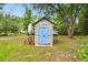 Charming shed with light blue double doors, a rooster weather vane, and a surrounding landscape at 9801 Pine Leaf Ln, Dade City, FL 33525