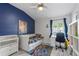 Cozy bedroom features a bright blue accent wall, ceiling fan, and sunny window at 10602 Rochester Way, Tampa, FL 33626