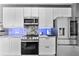 Well-lit kitchen with stainless appliances, white cabinetry, stylish backsplash, and modern lighting at 10602 Rochester Way, Tampa, FL 33626