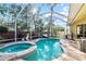 Screened-in pool and spa area with brick pavers, an outdoor kitchen, and comfortable seating at 10602 Rochester Way, Tampa, FL 33626