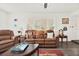 Cozy living room featuring a leather sofa, decorative pillows, shutters, and a patterned area rug over wood floors at 11777 90Th Ave, Seminole, FL 33772