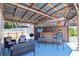 Outdoor bar featuring bar stools, tiki decor, grill, and wicker seating on painted deck at 11777 90Th Ave, Seminole, FL 33772