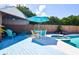 Poolside patio and spa area with an outdoor dining table, umbrella and chairs on painted decking at 11777 90Th Ave, Seminole, FL 33772