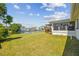 Backyard featuring a lush lawn, waterfront access, and exterior view of house with a covered deck at 13617 Frances Ave, Hudson, FL 34667