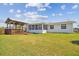 Exterior back view of the house and covered wooden deck with lush lawn at 13617 Frances Ave, Hudson, FL 34667