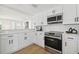 White kitchen featuring stainless steel appliances, white cabinetry, and hardwood floors at 13617 Frances Ave, Hudson, FL 34667