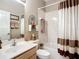 Well-lit bathroom featuring a vanity, toilet, and shower-tub combo with decorative curtain and storage at 146 Shell Falls Dr, Apollo Beach, FL 33572