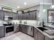 Modern kitchen with stainless steel appliances, gray cabinets, tile backsplash, and granite countertops at 146 Shell Falls Dr, Apollo Beach, FL 33572