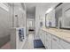 Bright bathroom showcasing a glass-enclosed shower, dual-sink vanity, and gray tile flooring at 15429 Caravan Ave, Odessa, FL 33556