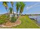Manicured backyard with lawn, landscaping, and direct access to waterfront dock and lake at 1806 Wolf Laurel Dr, Sun City Center, FL 33573