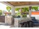 Covered outdoor kitchen with stone counter, stainless grill, bar seating, and ceiling fan at 182 E Canal Dr, Palm Harbor, FL 34684
