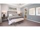 Comfortable bedroom with carpet flooring, tray ceiling, decorative wall art and access to ensuite at 1880 Longliner Loop, Wesley Chapel, FL 33543