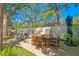 A brick patio is furnished with an outdoor dining set and lounge chairs, surrounded by trees and lawn at 207 S Coolidge Ave, Tampa, FL 33609