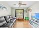 Comfortable living room featuring wood floors, a ceiling fan, and a cozy black leather sofa at 24076 Ragan Dr, Brooksville, FL 34601