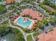 Aerial view of a large pool, palm trees, red sunshades, and building with a red tile roof at 2773 Via Cipriani # 1322A, Clearwater, FL 33764