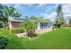 Home's backyard features a Florida room addition, lush green lawn, solar panels at 2814 Lomond Dr, Palm Harbor, FL 34684