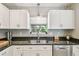 Bright kitchen featuring granite counters, stainless steel dishwasher, and white cabinets at 2815 W Estrella St, Tampa, FL 33629