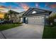 Inviting blue home showcasing a manicured lawn and a two-car garage at dusk at 30647 Walker Cup Pl, Wesley Chapel, FL 33543