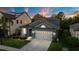 Well-maintained blue house with a lush green lawn and a convenient two-car garage at dusk at 30647 Walker Cup Pl, Wesley Chapel, FL 33543
