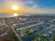 Aerial view of a waterfront neighborhood with canals, homes, and the sun setting over the ocean at 4116 Diaz Ct, Hernando Beach, FL 34607