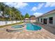 Backyard featuring a pool, spa, stone patio, and beautifully landscaped surroundings at 5189 Brackenwood Dr, Spring Hill, FL 34609