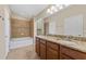 Bright bathroom with dual sinks, granite countertop, tiled shower, and a separate bathtub at 5717 Kingletsound Pl, Lithia, FL 33547