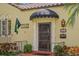 Close up of yellow house front door with black awning and mature landscape at 646 16Th Ne Ave, St Petersburg, FL 33704