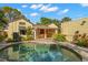 Backyard pool area with stone patio, lush landscaping, and covered patio with orange curtains at 646 16Th Ne Ave, St Petersburg, FL 33704