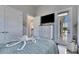 Bright bedroom with a balcony view, wall-mounted TV, and light blue bedding at 706 Manns Harbor Dr, Apollo Beach, FL 33572