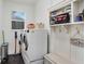 Bright laundry room with a modern washer and dryer, a storage shelf, and dark tile flooring at 7113 S Mascotte St, Tampa, FL 33616