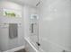 Bathroom with tub and shower, glass doors, and white tile at 827 Virginia St, Dunedin, FL 34698