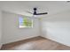 Sunlit bedroom featuring hardwood flooring, modern ceiling fan, and large window at 8512 Longboat Ln, Hudson, FL 34667