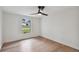 Bright bedroom features sleek hardwood floors, a ceiling fan, and a large window view at 8512 Longboat Ln, Hudson, FL 34667