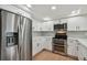 Modern kitchen features stainless steel appliances, white cabinetry, and a light gray tiled backsplash at 8512 Longboat Ln, Hudson, FL 34667