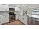 Modern kitchen with stainless appliances, white cabinets, quartz countertops, and tile backsplash at 8512 Longboat Ln, Hudson, FL 34667
