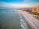 Picturesque aerial view featuring a sandy beach, a pier, and a bustling coastal town at 864 Mandalay Ave, Clearwater Beach, FL 33767