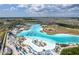 Aerial view of a large lagoon with sandy beaches, palm trees, and various water activities at 8720 Drummer Plank Dr, Wesley Chapel, FL 33545