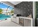 Covered outdoor kitchen with stainless steel grill and fridge, overlooking the pool at 8720 Drummer Plank Dr, Wesley Chapel, FL 33545
