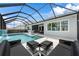 This stunning pool area boasts a screened enclosure, waterfall feature, in-pool loungers, and ample seating for entertaining at 8720 Drummer Plank Dr, Wesley Chapel, FL 33545