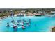 Aerial view of a crystal clear lagoon with inflatables, a waterslide, and sandy beach at 8720 Drummer Plank Dr, Wesley Chapel, FL 33545