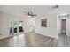 Bright and airy living room with wood-look floors, a ceiling fan, and large window for natural light at 8846 Hunter Dr, New Port Richey, FL 34653