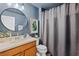 Charming bathroom with blue walls, round mirror, and a shower with a gray patterned curtain at 9607 Orange Jasmine Way, Tampa, FL 33647