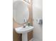 Small powder room featuring a pedestal sink and round mirror at 11260 Kapok Grand Cir, Madeira Beach, FL 33708