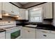 Well lit kitchen featuring white cabinets, dark countertops, and modern appliances at 11487 80Th Ave, Seminole, FL 33772