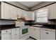 Well lit kitchen featuring white cabinets, dark countertops, and modern appliances at 11487 80Th Ave, Seminole, FL 33772