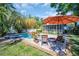 Backyard pool with a striped umbrella and lounge chairs, surrounded by palm trees at 1226 Serpentine S Dr, St Petersburg, FL 33705