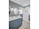 Vanity with double sinks, storage cabinets, lighting, and a doorway to the water closet at 1226 Serpentine S Dr, St Petersburg, FL 33705