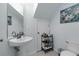 Clean and functional powder room features a pedestal sink, toilet, and a convenient storage rack at 12937 Trade Port Pl, Riverview, FL 33579