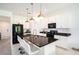 Modern kitchen featuring white cabinets, black appliances, a granite countertop island with seating and gold pendant lights at 13802 Kinsale St, Riverview, FL 33579